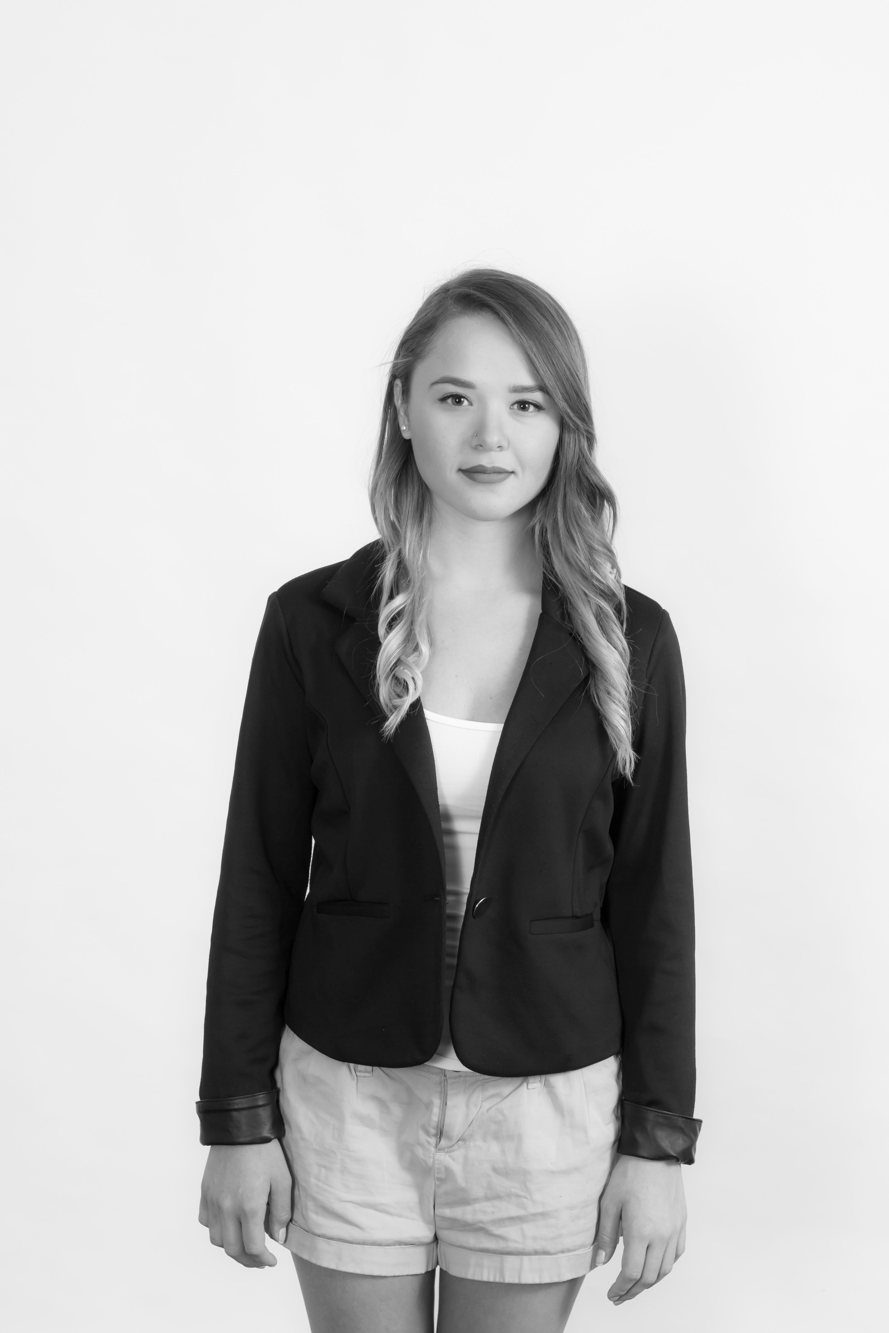 Elegant grayscale portrait of a woman wearing a black blazer in a studio setting.