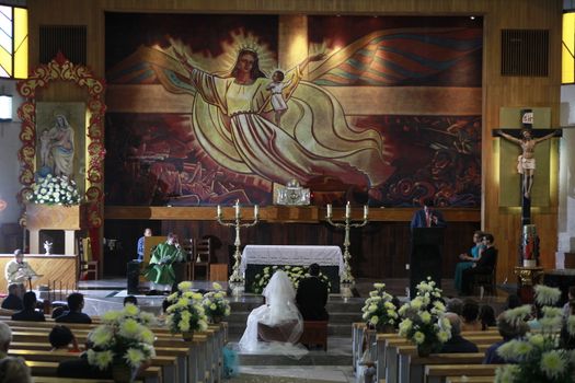 Elegant church wedding ceremony capturing bride and groom at the altar with attendees in a detailed religious setting.
