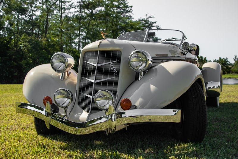 Front view of cream-colored vintage automobile on grass