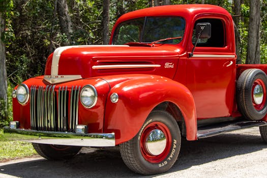 Classic red Ford truck from the 1940s featuring iconic design, parked in nature.