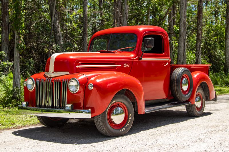 Classic red Ford truck parked in vibrant green forest