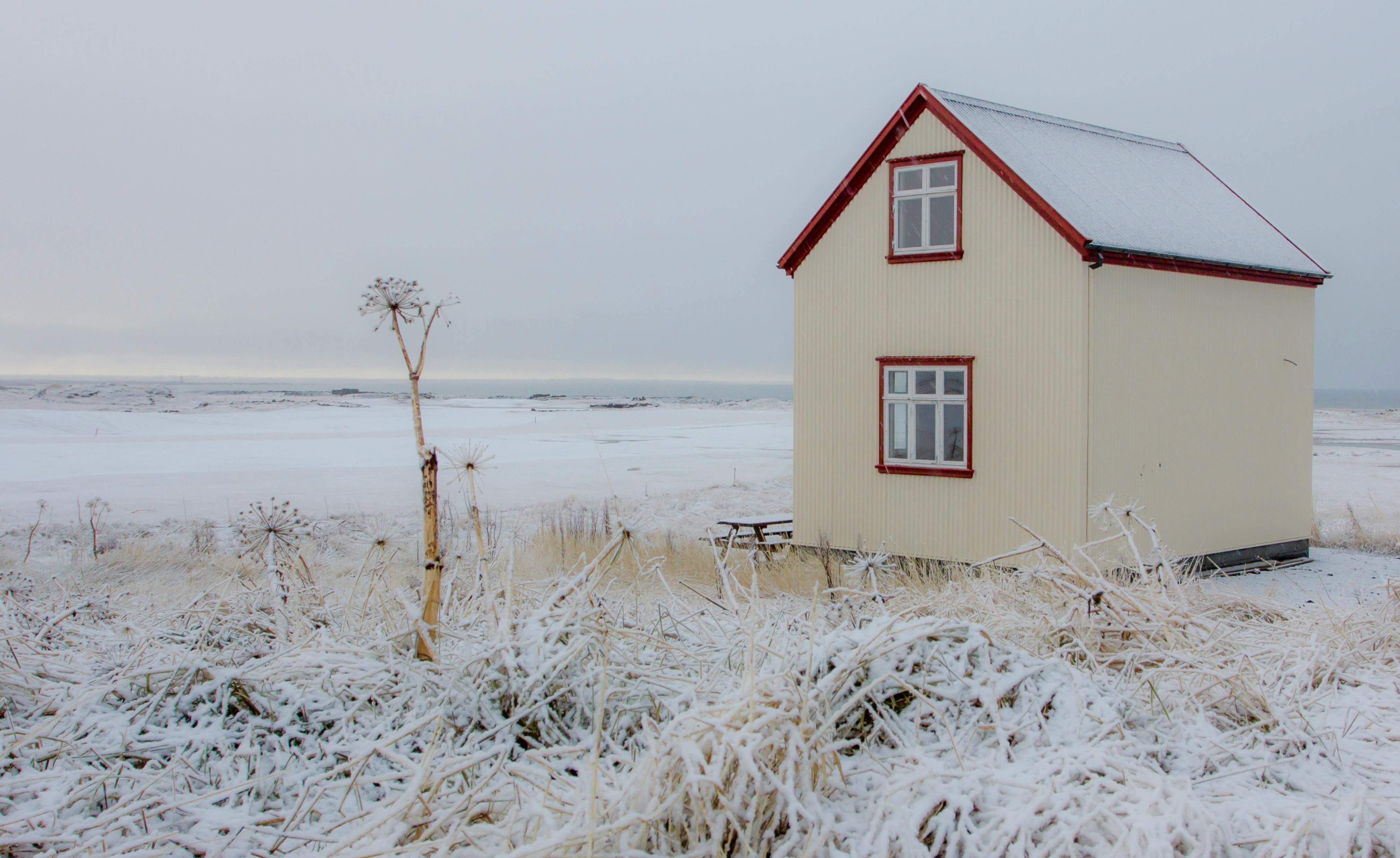 A cozy cabin surrounded by snow in Vogar, Iceland, captures the serene beauty of winter.