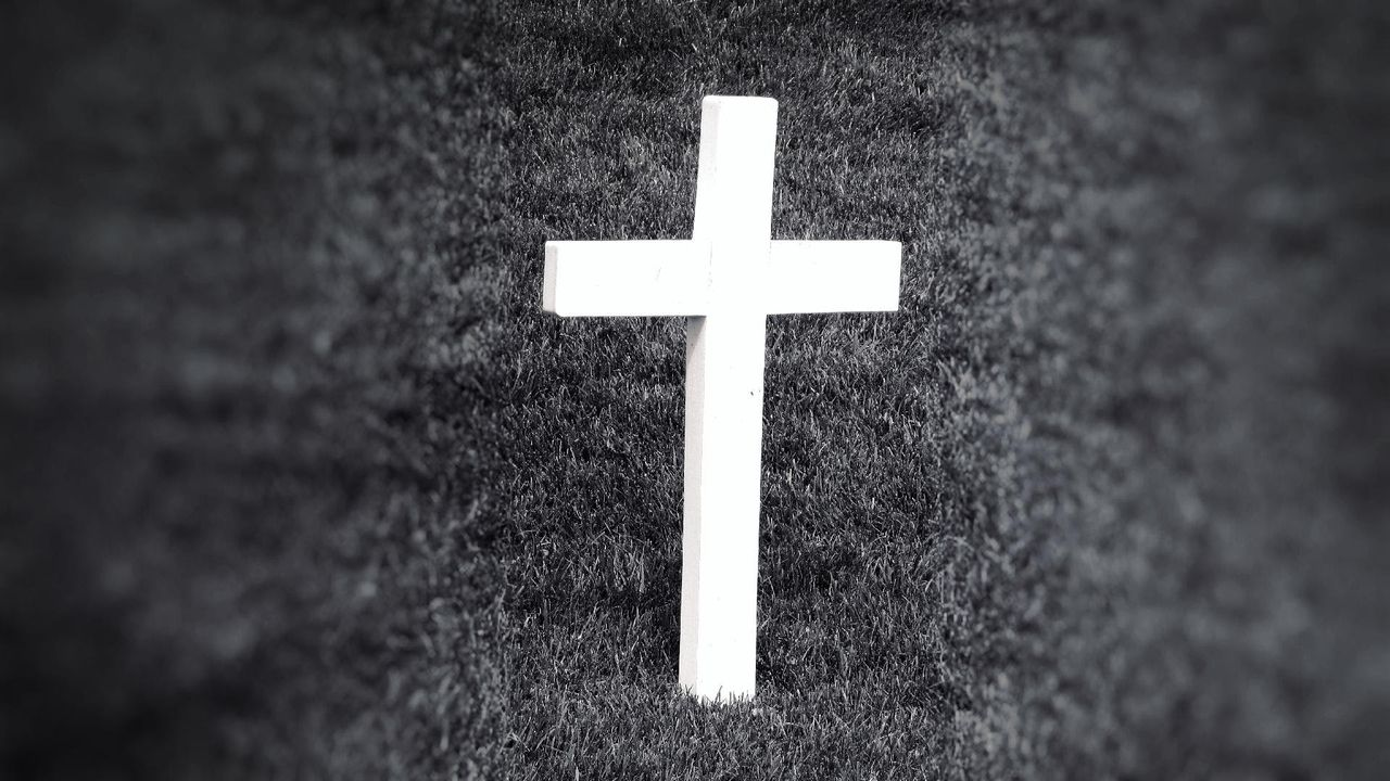 black and white image of a cross standing in grass symbolizing spiritu