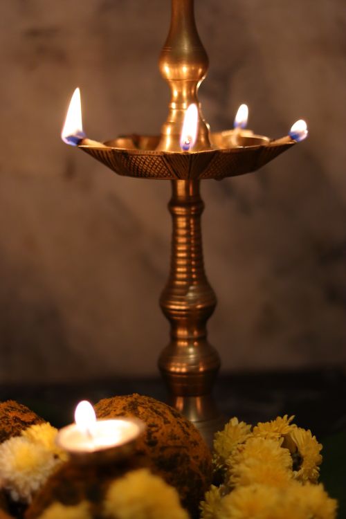 Free Brass lamp with flames surrounded by yellow flowers, creating a warm ambiance. Stock Photo