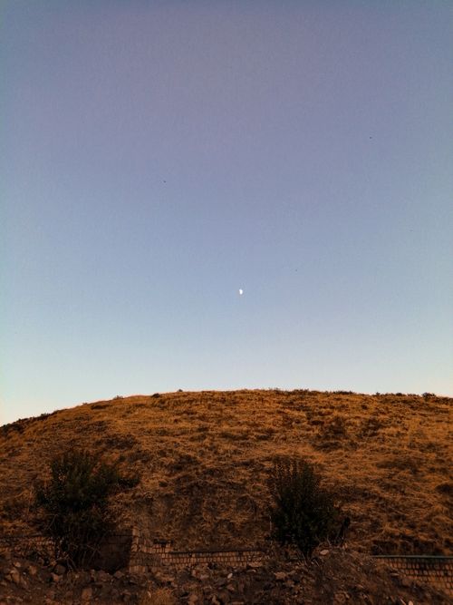 Free Peaceful evening scene with moon over a dry hill, creating a serene atmosphere. Stock Photo