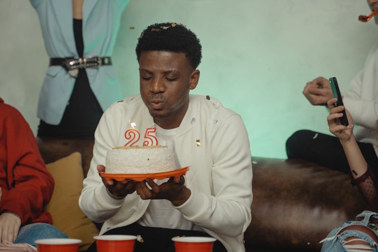 A Man Blowing A Birthday Cake