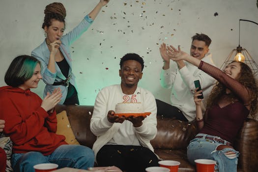 A diverse group of friends celebrates a 25th birthday indoors with cake and confetti.