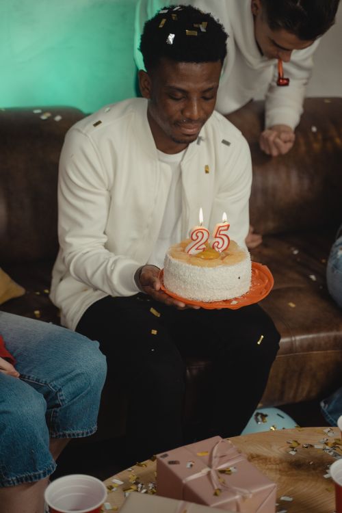Free A man in a festive setting celebrates his 25th birthday with a cake and candles. Stock Photo