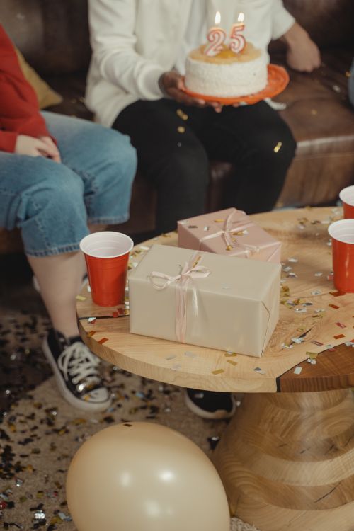 Free An indoor birthday celebration with cake, gifts, and confetti on a wooden table. Stock Photo