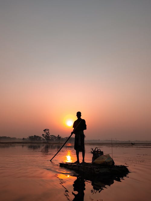 Free Silhouette of Man Standing on a Raft during Sunset Stock Photo