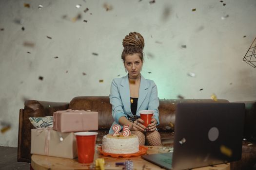 A woman celebrates her 25th birthday alone with a cake, gifts, and virtual setup.