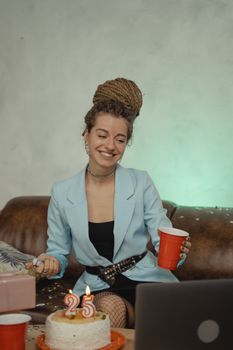 Smiling woman having a virtual birthday party with cake, candles, and confetti.