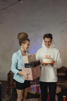 两个年轻人在室内庆祝生日，享用蛋糕和礼物