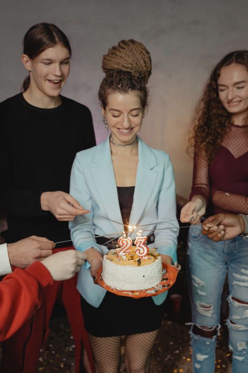 Free A group of friends joyously celebrate a 23rd birthday with a cake and candles indoors. Stock Photo