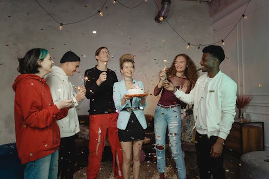 Group of friends celebrating a birthday indoors with enthusiasm and confetti.