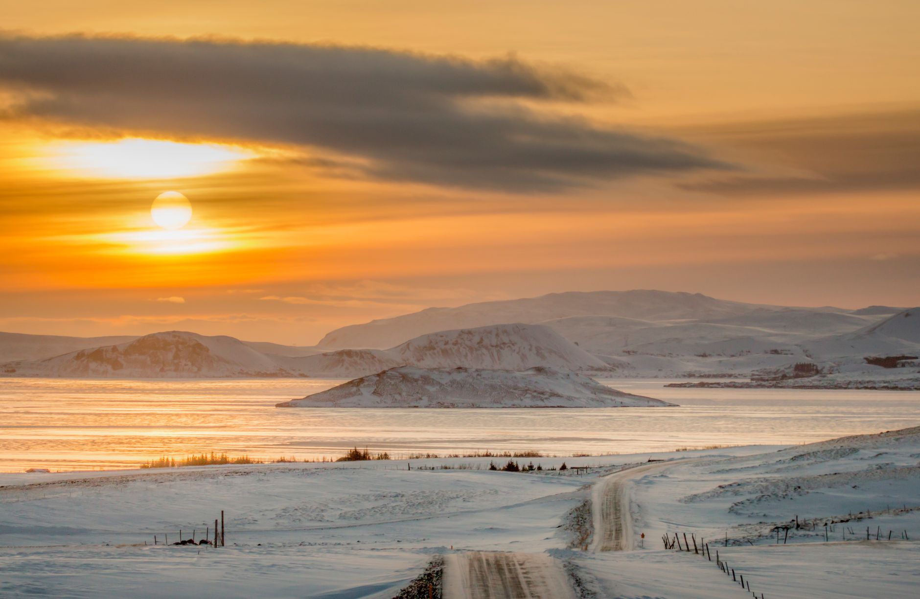 Beautiful winter sunrise over Icelandic landscapes with snow-covered roads and mountains.