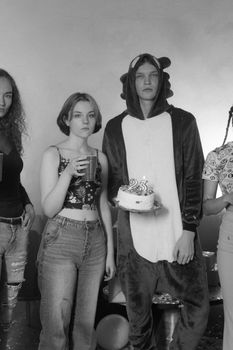 A black and white photo of friends celebrating a birthday with a cake and costumes.