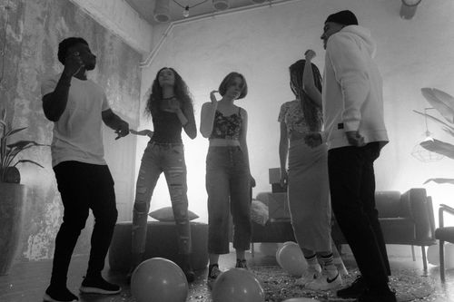 Free Black and white image of friends dancing and celebrating indoors with balloons and confetti. Stock Photo