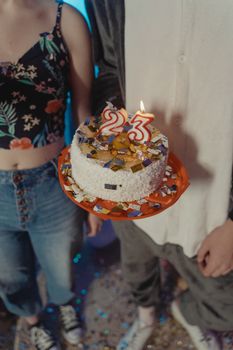 A birthday cake with number 23 candles, surrounded by confetti, creating a festive indoor atmosphere.