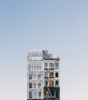 A minimalist facade of a New York building with a neon sign against a clear sky.