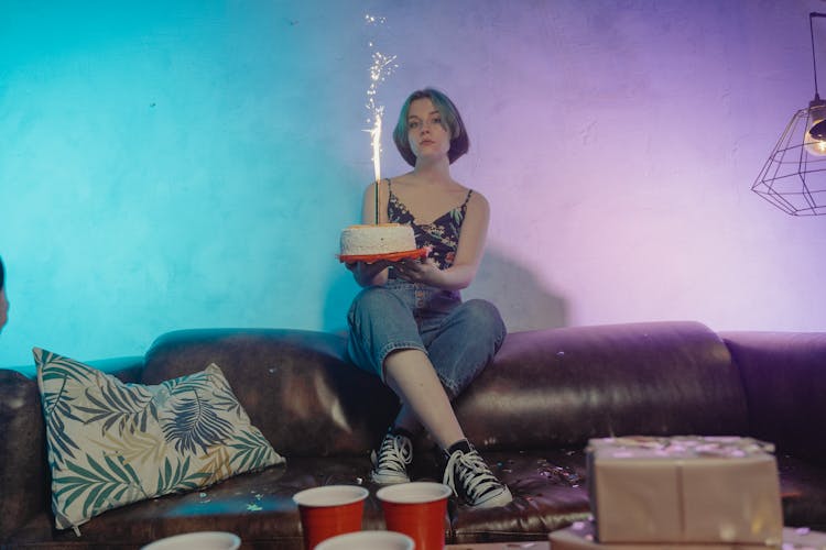 A Woman Holding A Birthday Cake With Firecracker