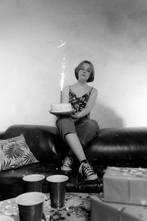 A Woman Sitting on a Couch while Holding a Cake