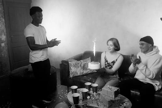 A lively birthday celebration featuring a cake with sparklers and friends clapping in black and white setting.