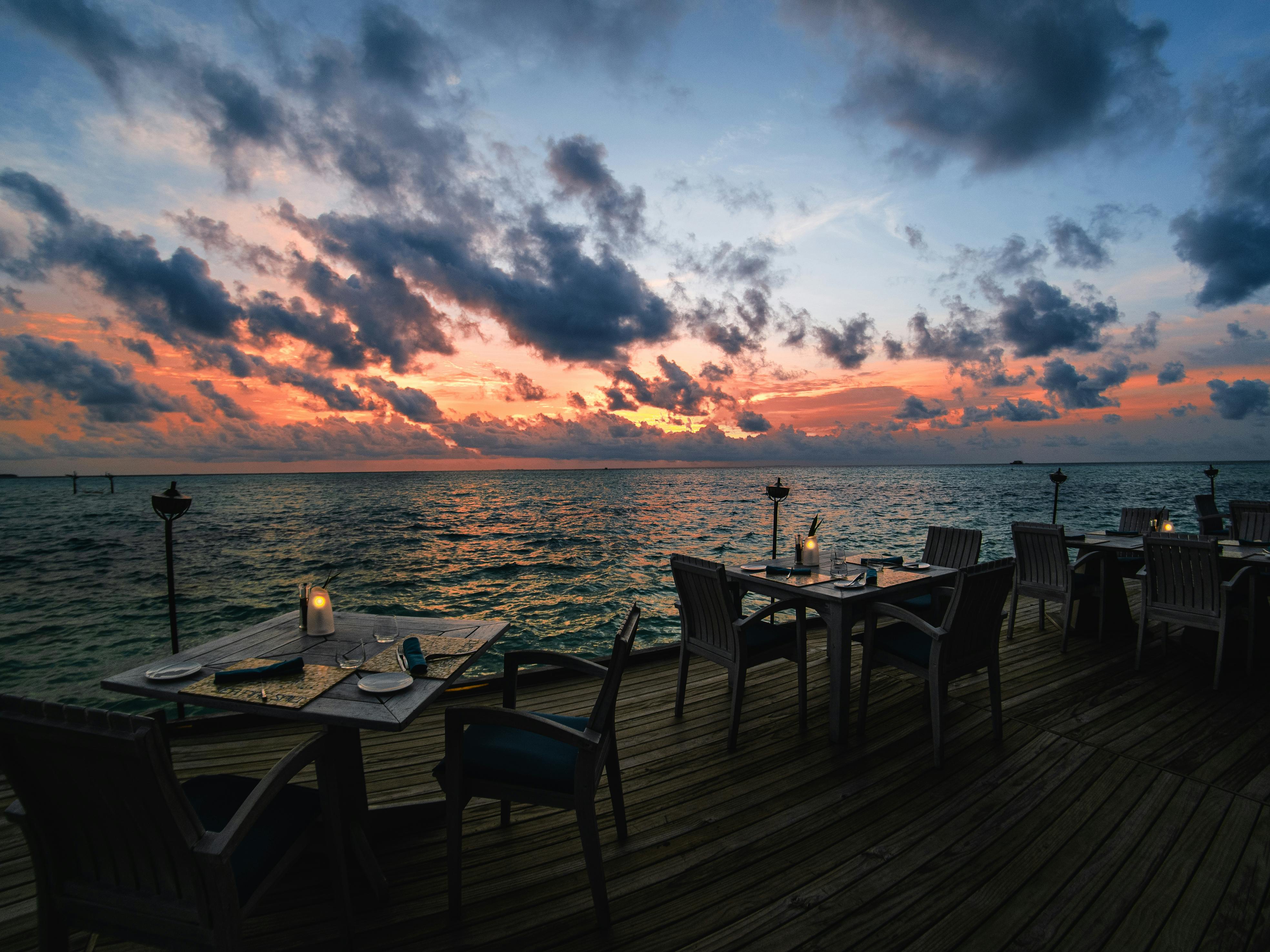 Oceanfront table setting at sunset with wine glasses and the Pacific horizon - malibu beach restaurants