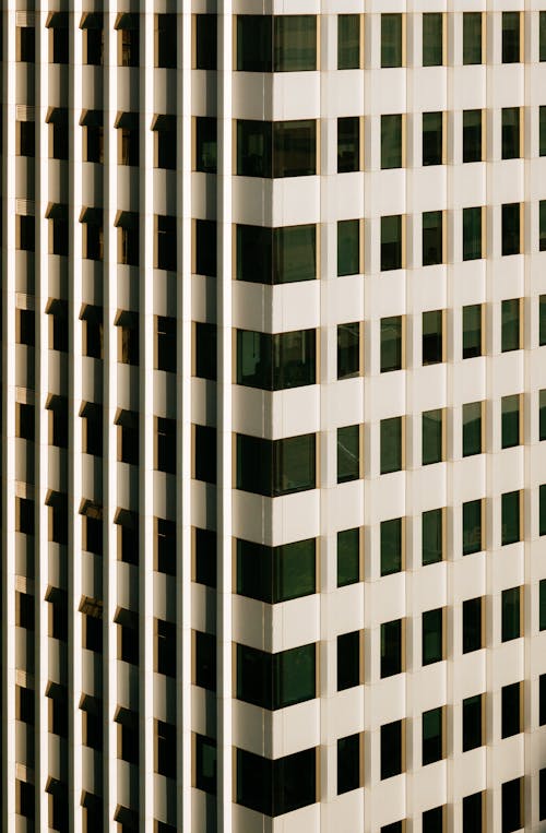 Background of high rise building with rows of white panels and windows in daylight