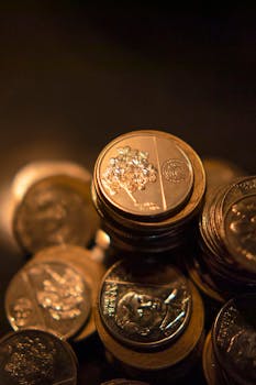 A detailed vertical shot of stacked coins, beautifully illuminated with a warm, golden glow.