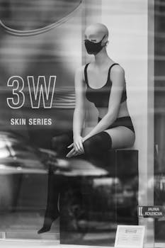 Grayscale image of a mannequin wearing lingerie in a fashion store display.