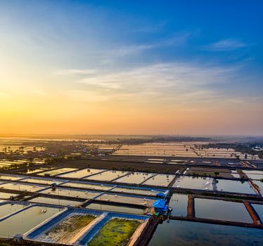A breathtaking aerial view of fish ponds at sunset in West Java, Indonesia, showcasing a serene, colorful landscape.