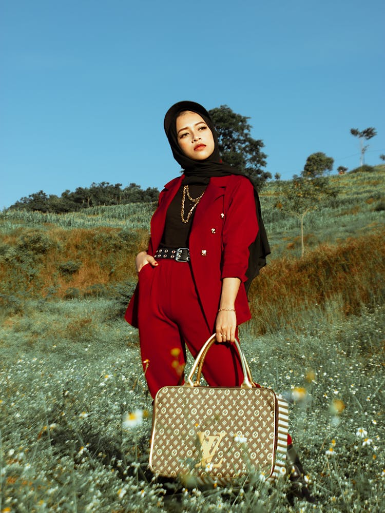 A Woman In Red Blazer And Pants Holding A Louis Vuitton Bag