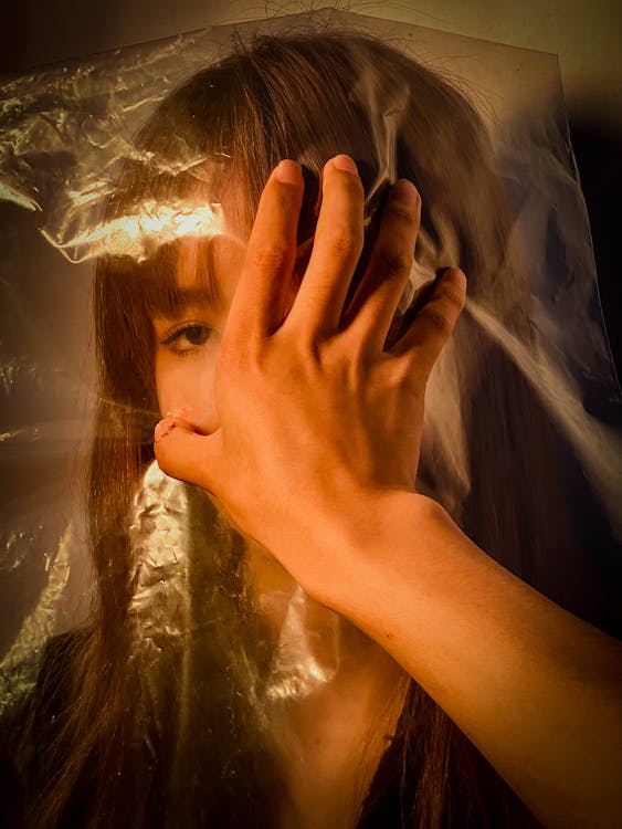 Free Hopeless ethnic female feeling lack of air behind plastic bag and hand covering mouth Stock Photo