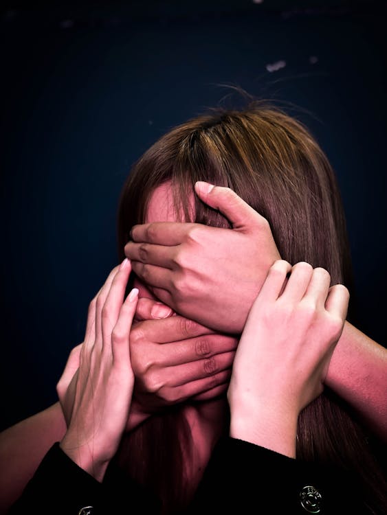 People covering face and mouth of helpless woman