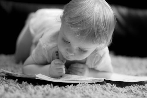 Grayscale Photo of Baby Scribbling on Notebook