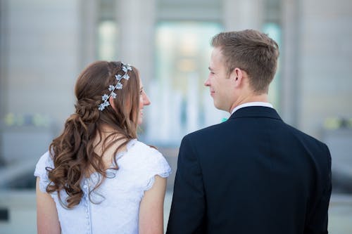 Uomo In Piedi Accanto A Donna Che Indossa Abito Bianco Con Maniche Ad Aletta