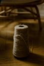 Big spool of gray woolen thread used for knitting located on wooden floor near chair in cozy apartment