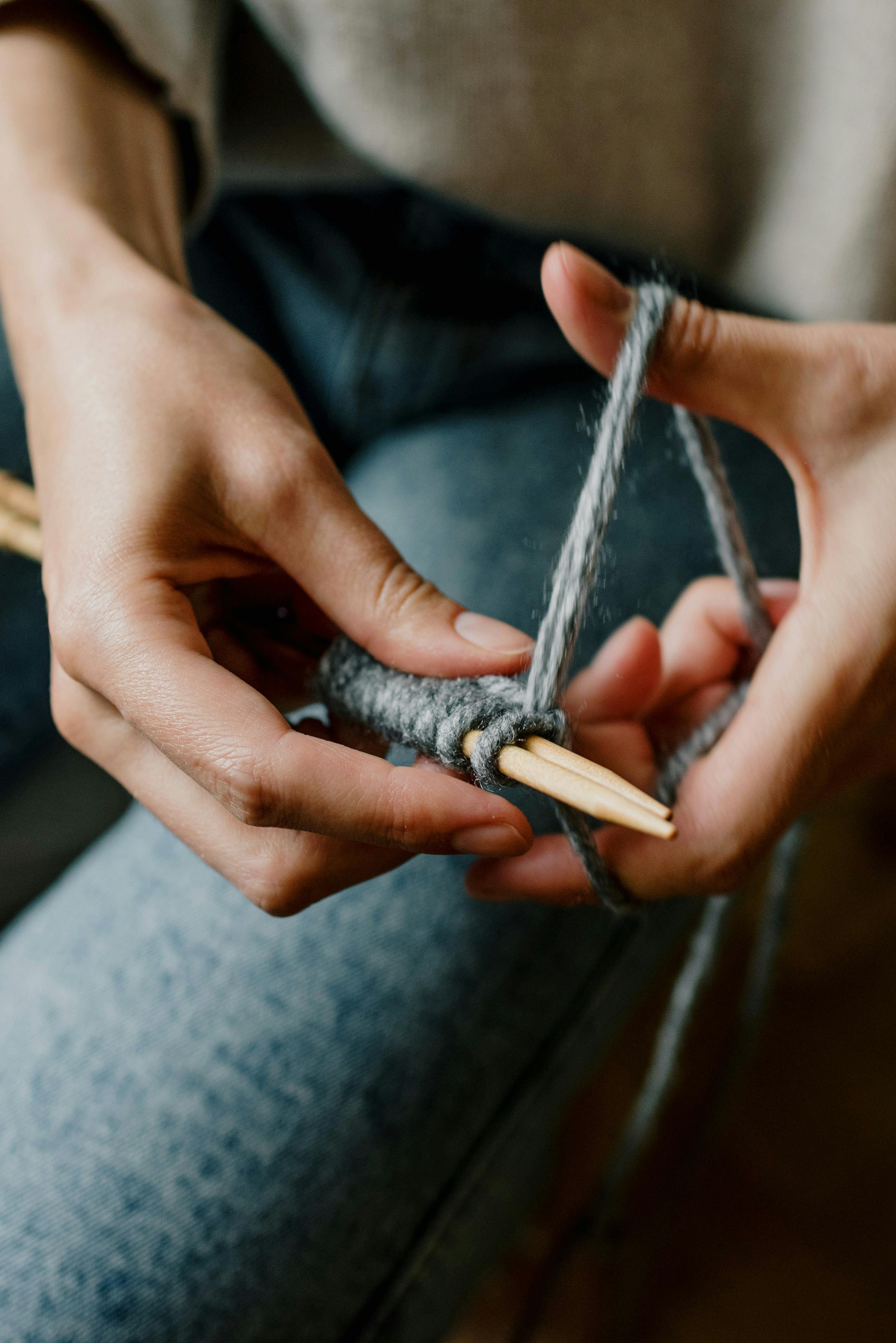 A close-up view of a woman knitting with gray yarn, showcasing the art of craft and creativity.