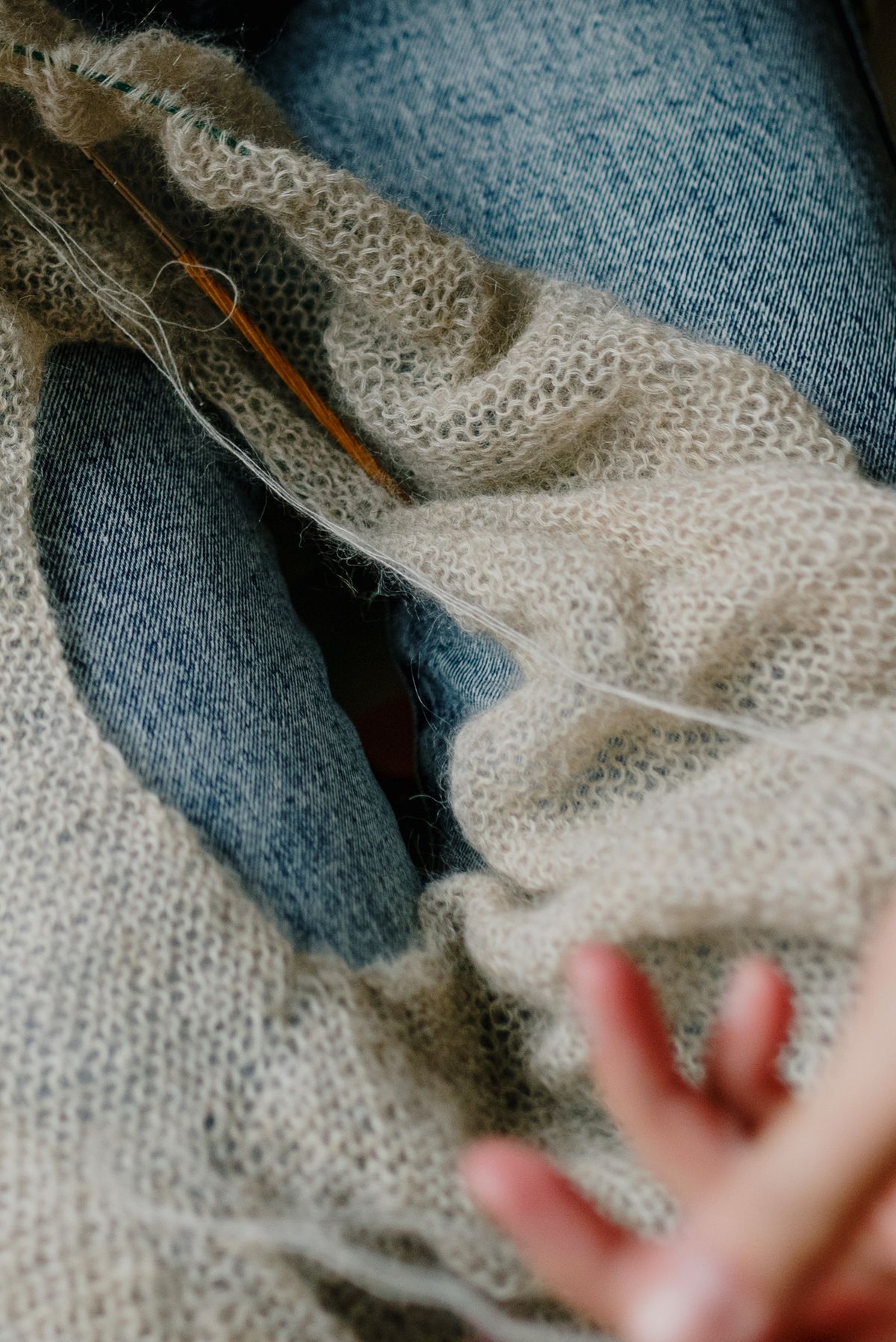Knitted wool fabric with knitting needles on a denim background