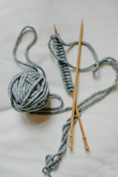 Knitting needles and yarn in a close-up top view on a white background.