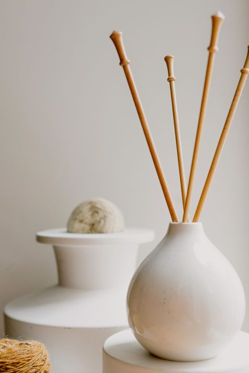 Free Minimalist still life featuring a ceramic vase with bamboo sticks and modern decor elements. Stock Photo