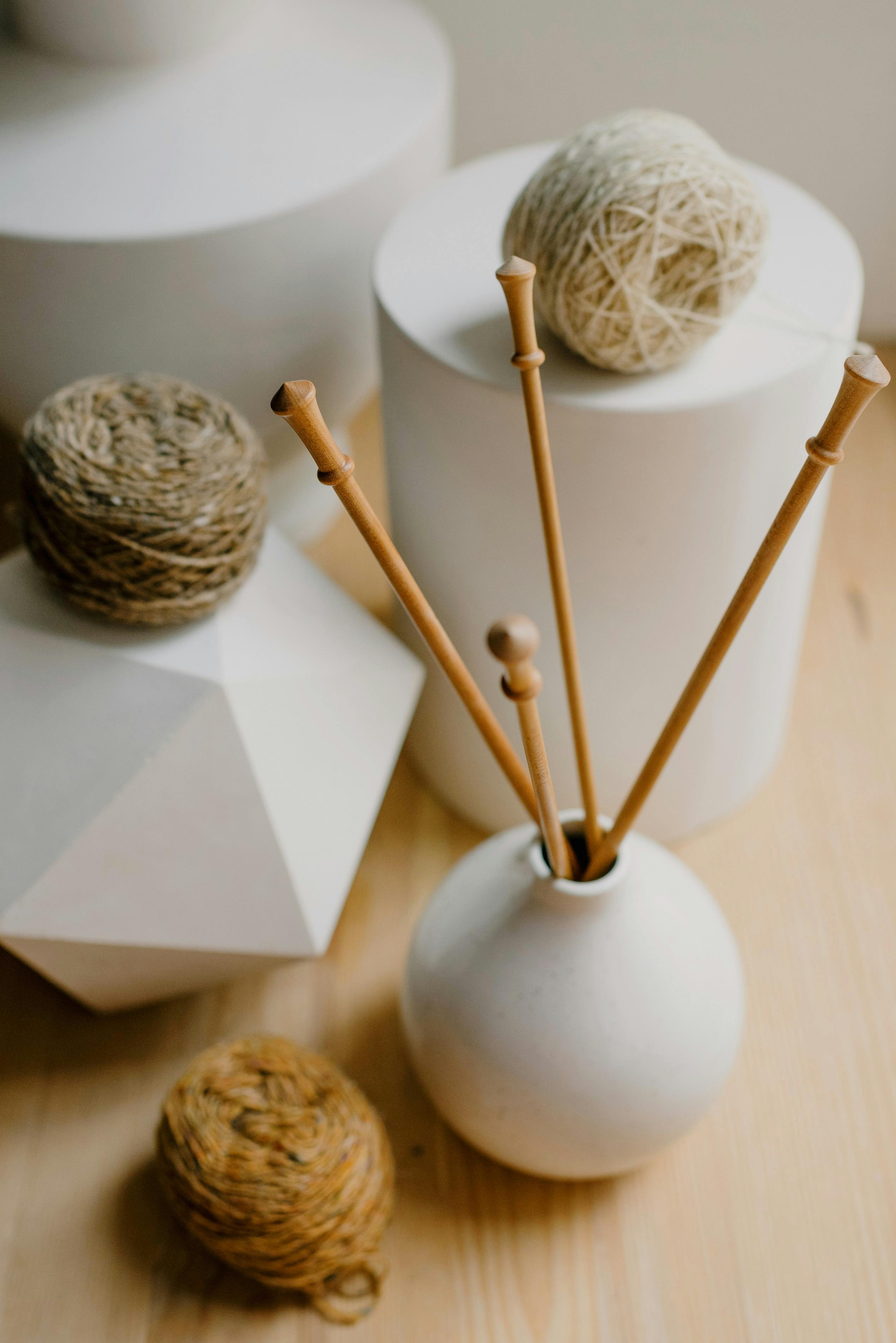 Stylish arrangement of wooden knitting needles with earthy yarns on geometric backgrounds.