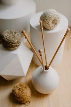Stylish arrangement of wooden knitting needles with earthy yarns on geometric backgrounds.