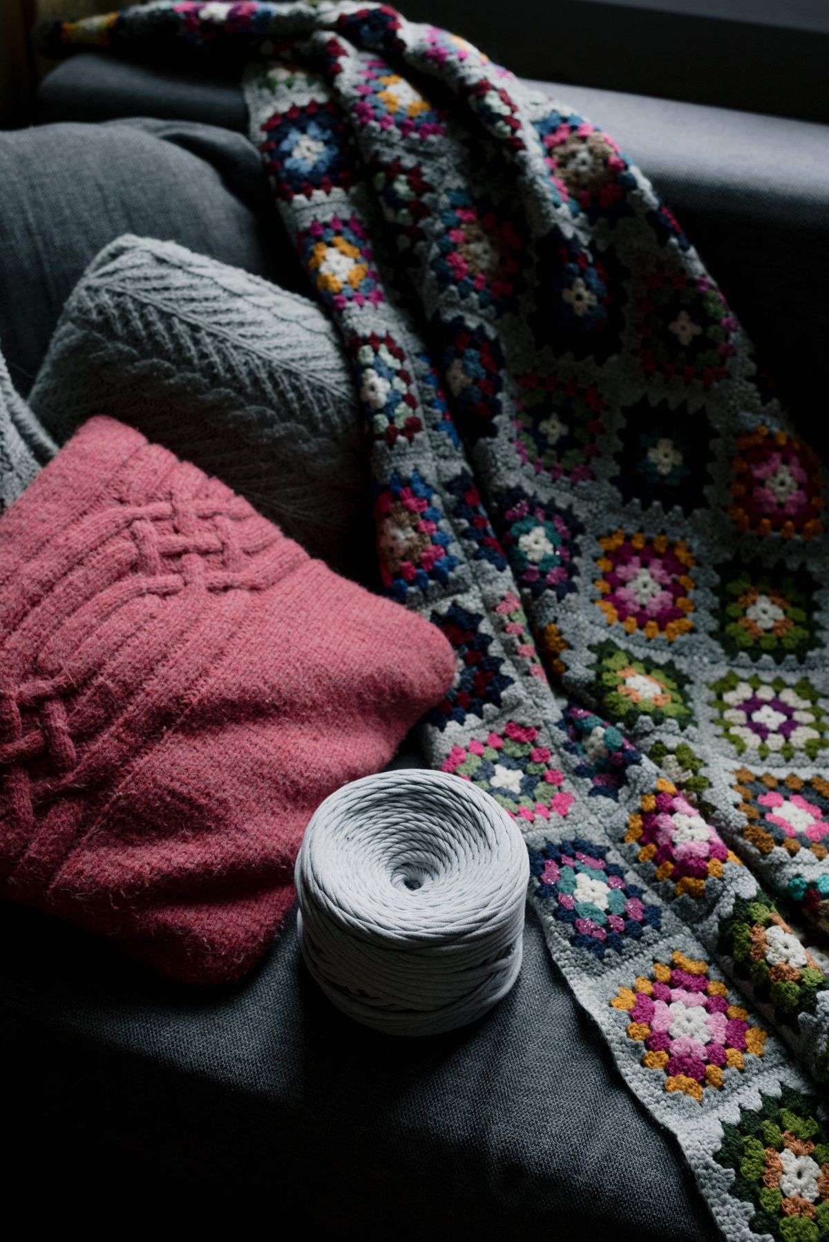 Colorful crochet blanket with yarn on a cozy couch, perfect for winter warmth.