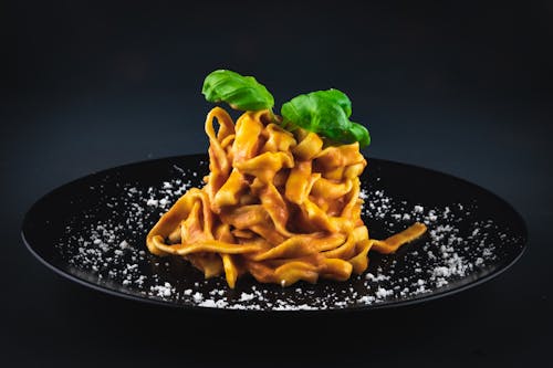 Free Pasta With Green Leaf on Black Plate Stock Photo