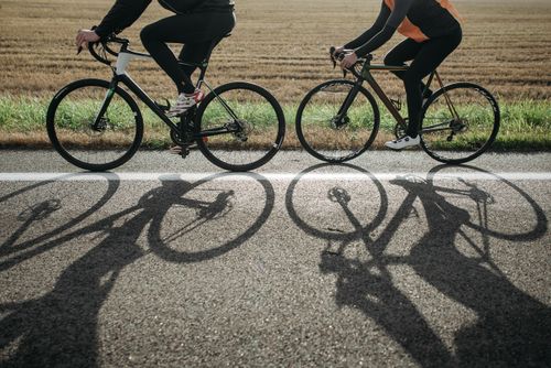 Free Two cyclists enjoying a ride on a sunny day along a scenic country road. Stock Photo