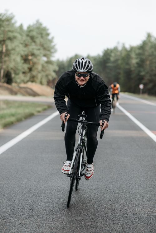 Free Cyclist riding on a tranquil road in nature, showcasing active lifestyle and fitness. Stock Photo