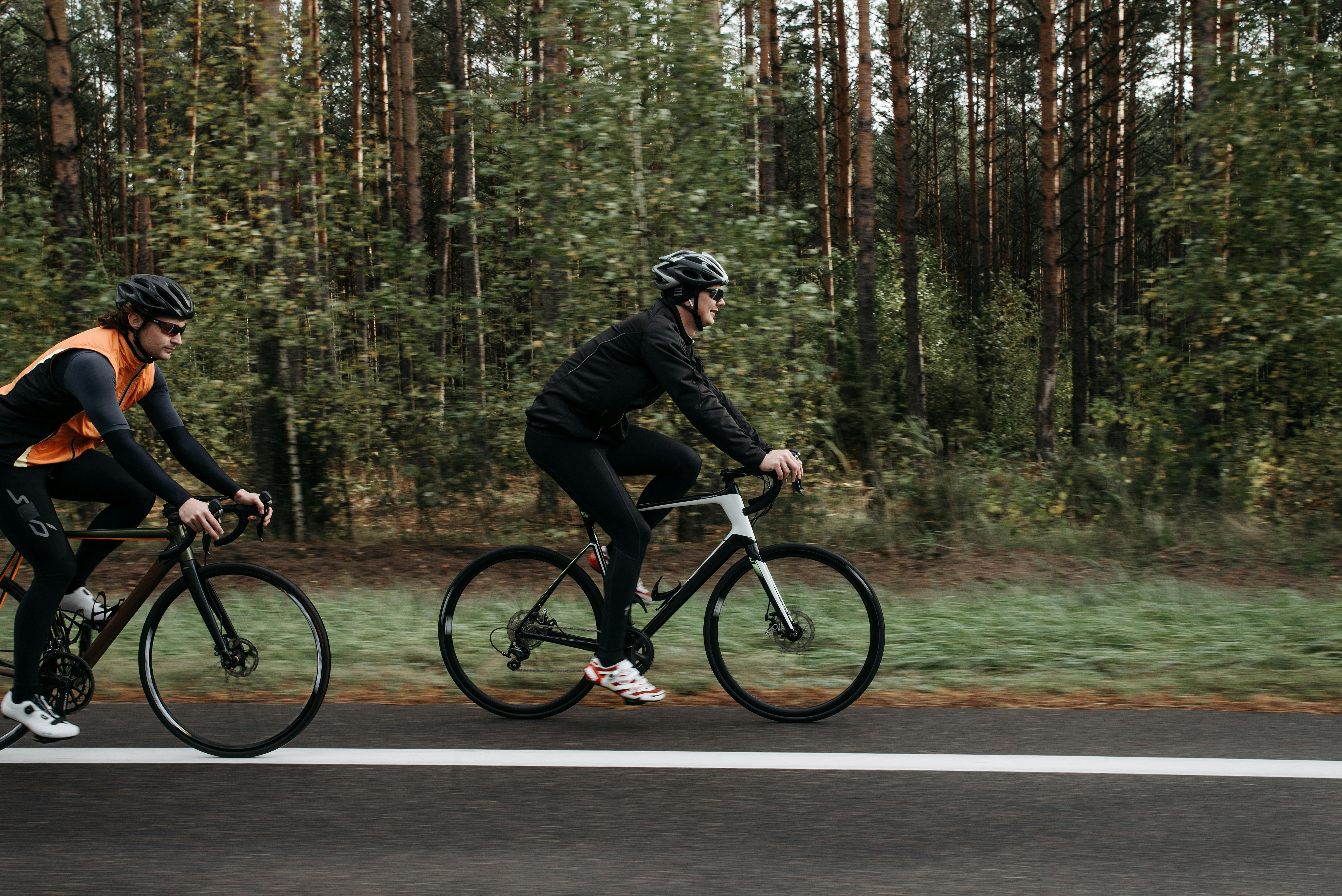 Two cyclists ride along a forest road enjoying a peaceful outdoor journey.