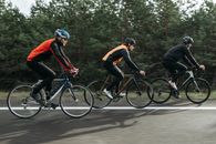 三名男子在风景秀丽的户外道路上一起骑自行车，展现了团队合作与运动能力